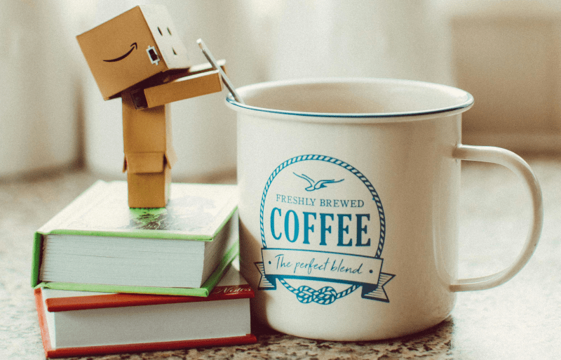 Foto de um micro robô humanóide agitando o café em uma chícara gigante.